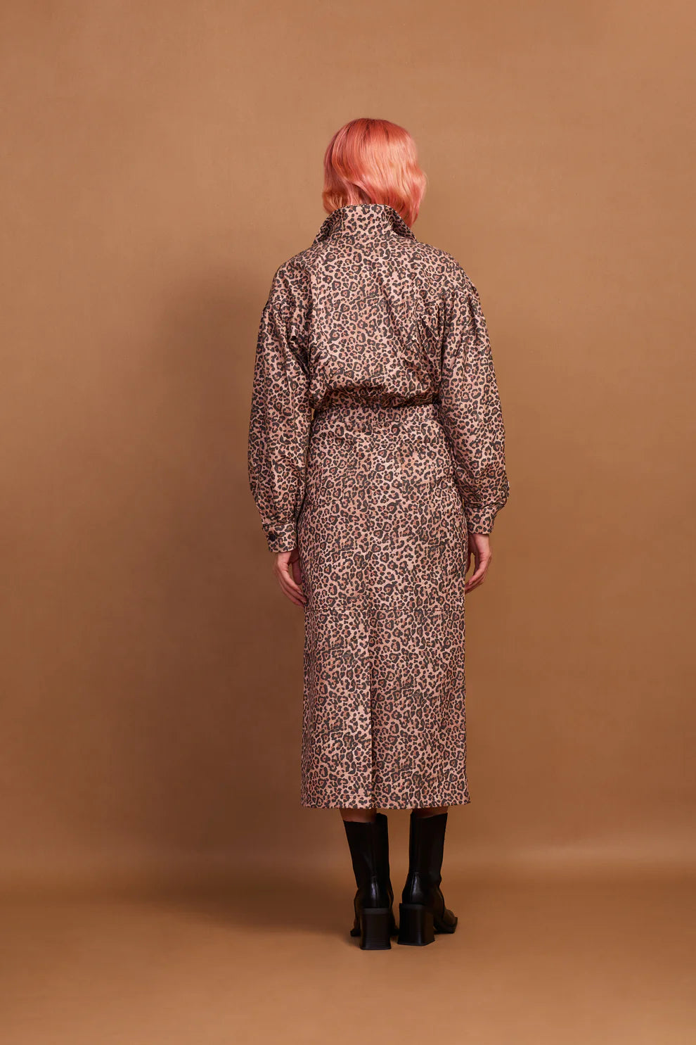 A model wearing a brown animal print zip jacket and standing against a plain background.