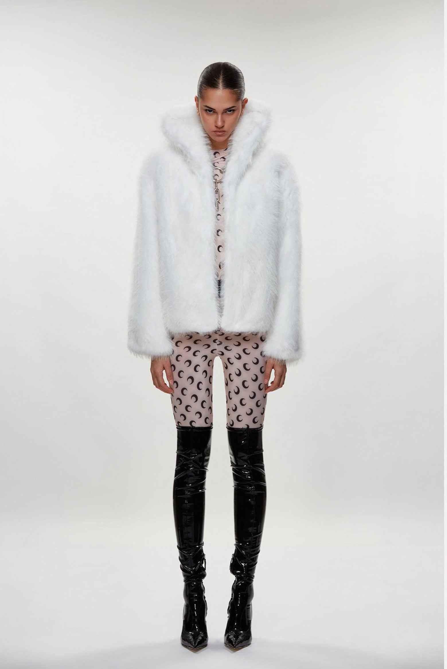 Person wearing a white fur coat, patterned pants, and black boots on a white background