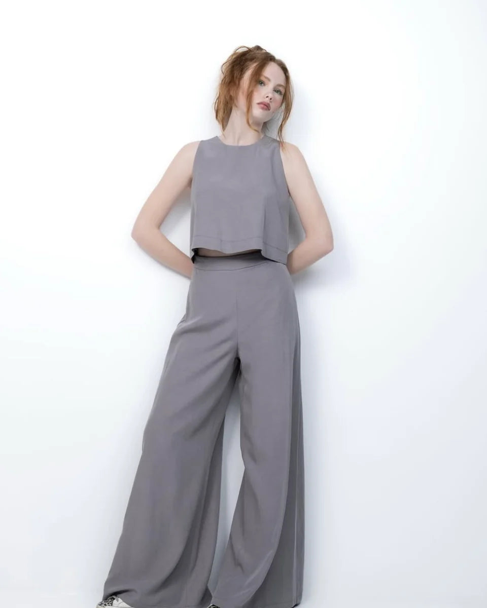 Woman wearing a gray sleeveless top and wide-leg pants on a white background