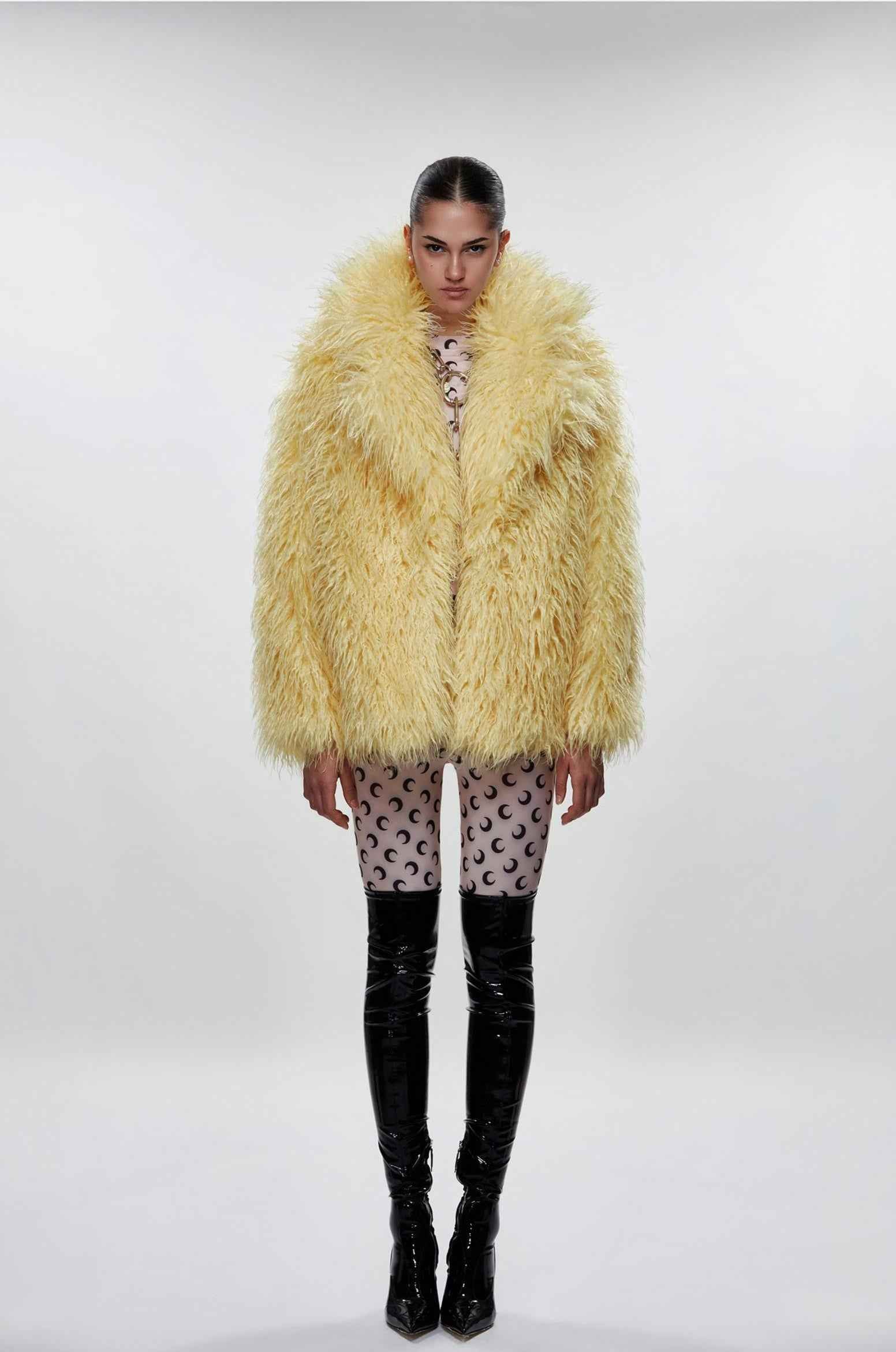 Person wearing a fluffy yellow coat on a plain background