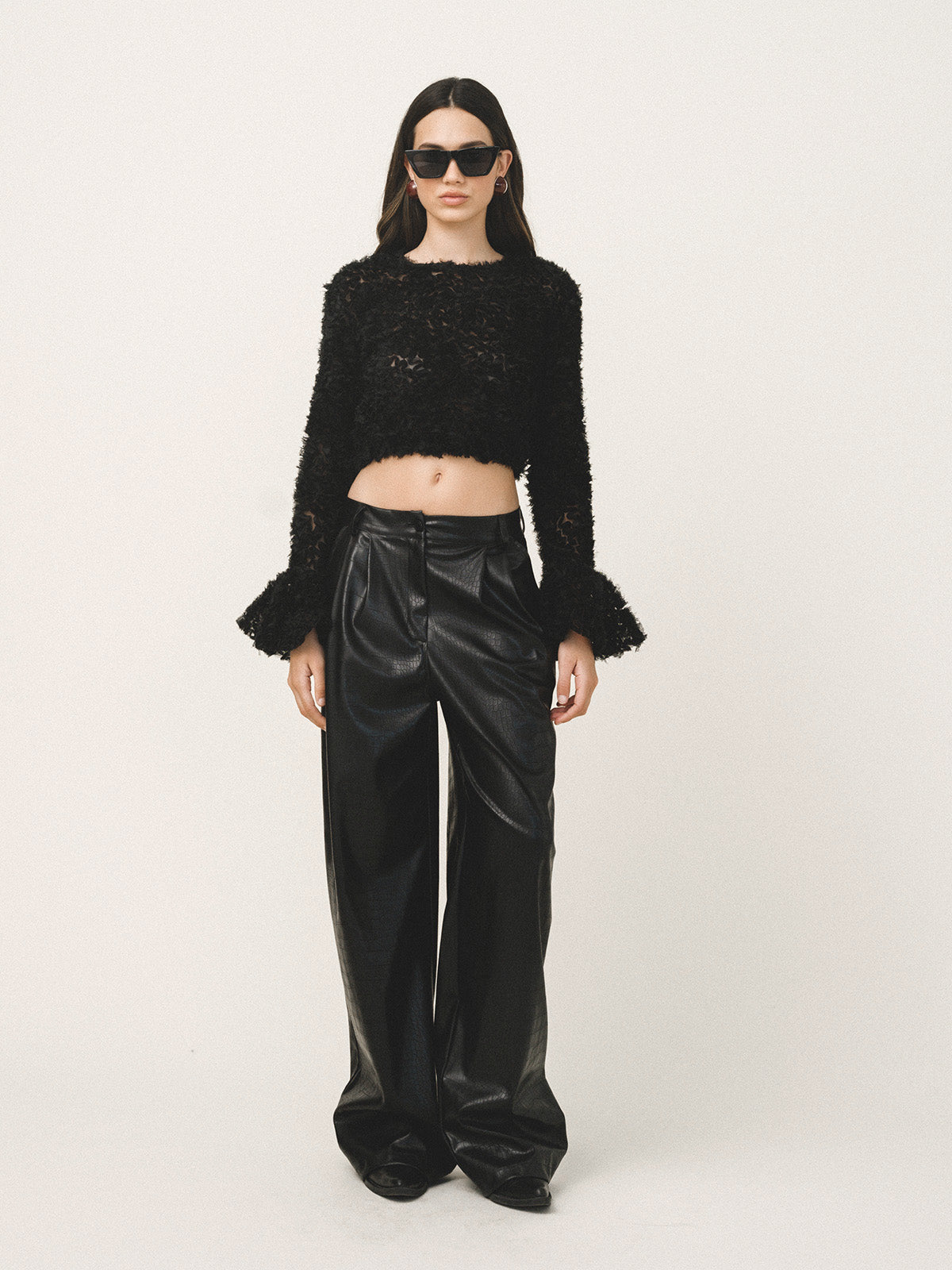 Woman wearing a black sequin top and black pants on a white background