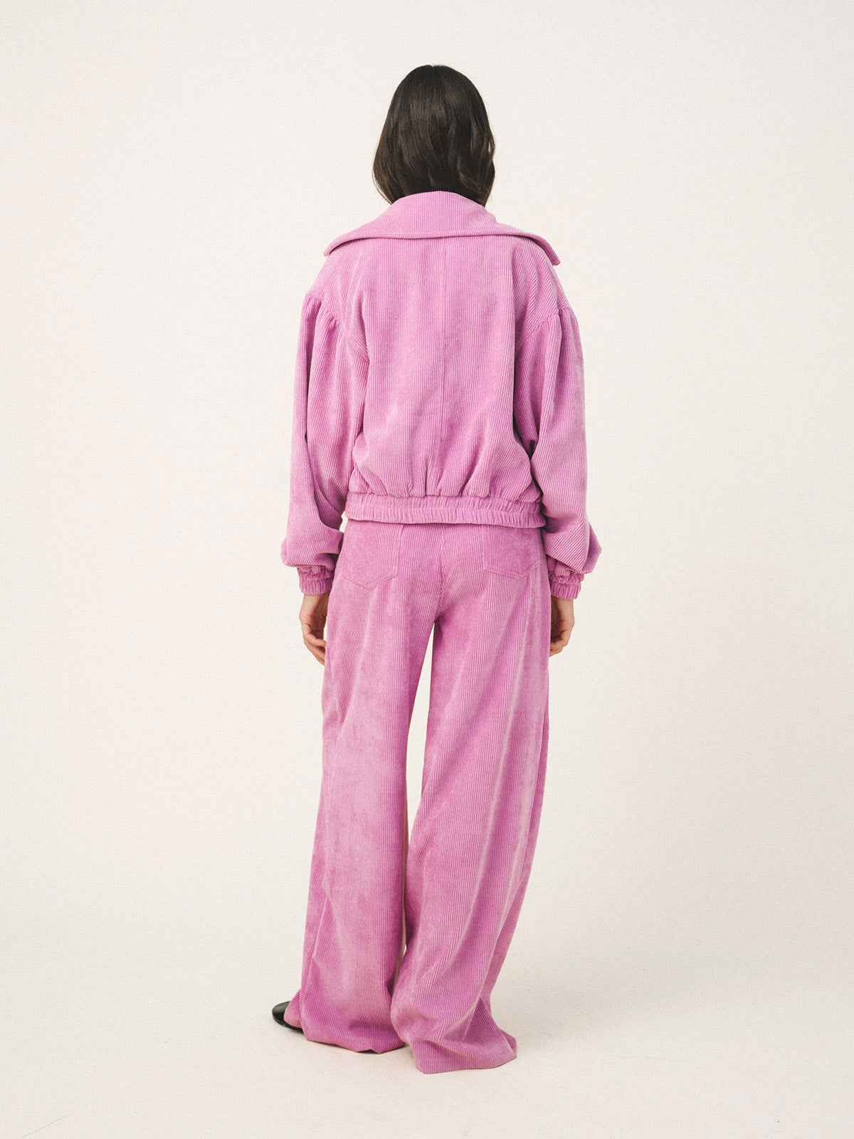 Person wearing a pink tracksuit on a white background