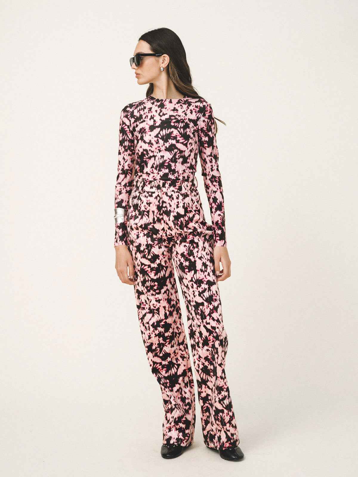 Woman wearing a pink floral jumpsuit on a white background