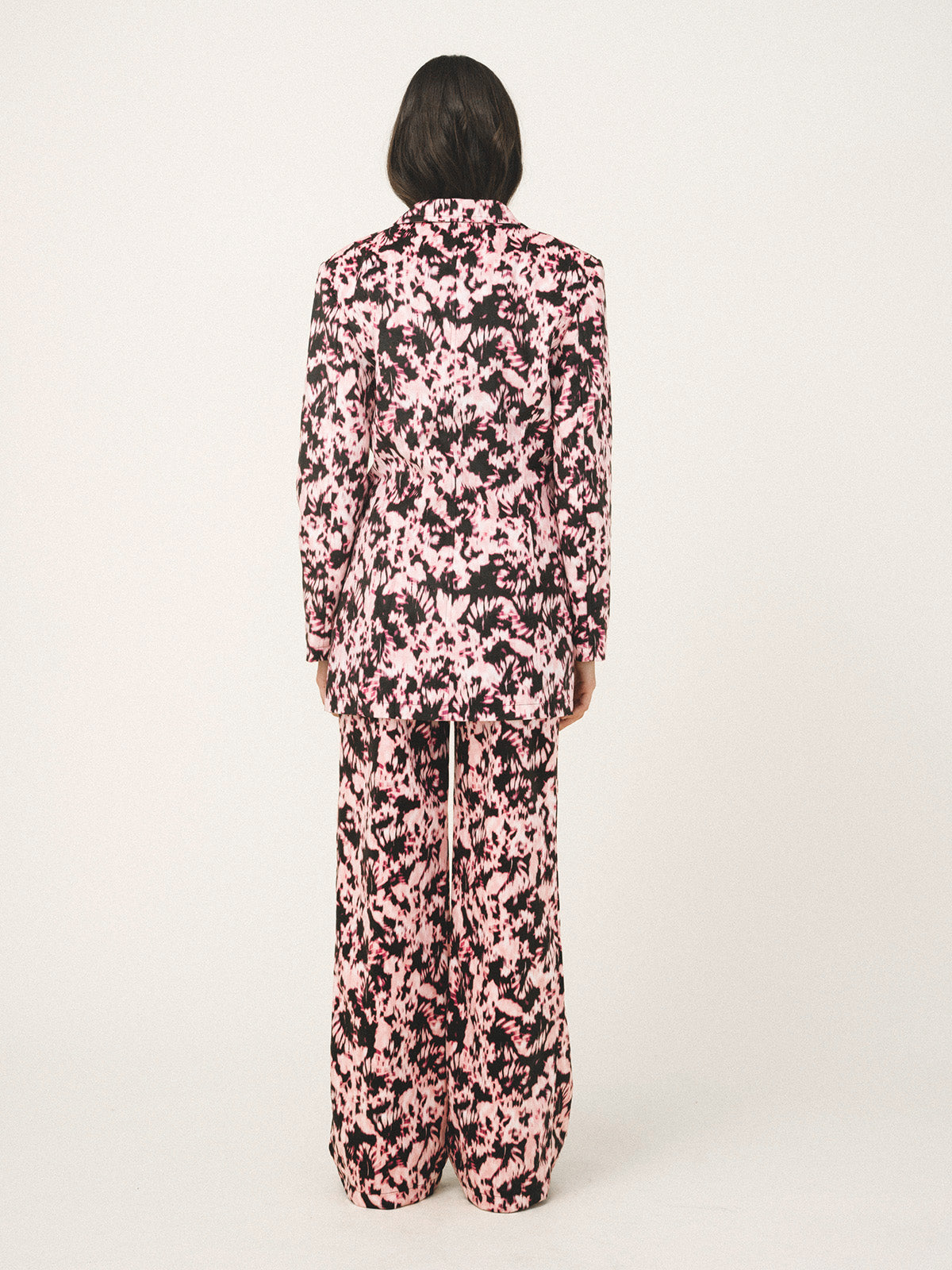 Person wearing a pink and black floral jumpsuit on a white background