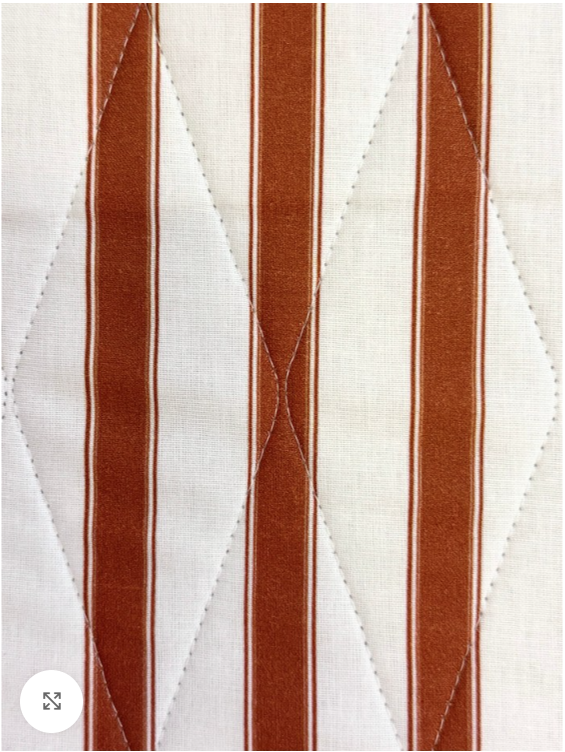 Close-up of brown and white striped fabric with a quilted pattern.