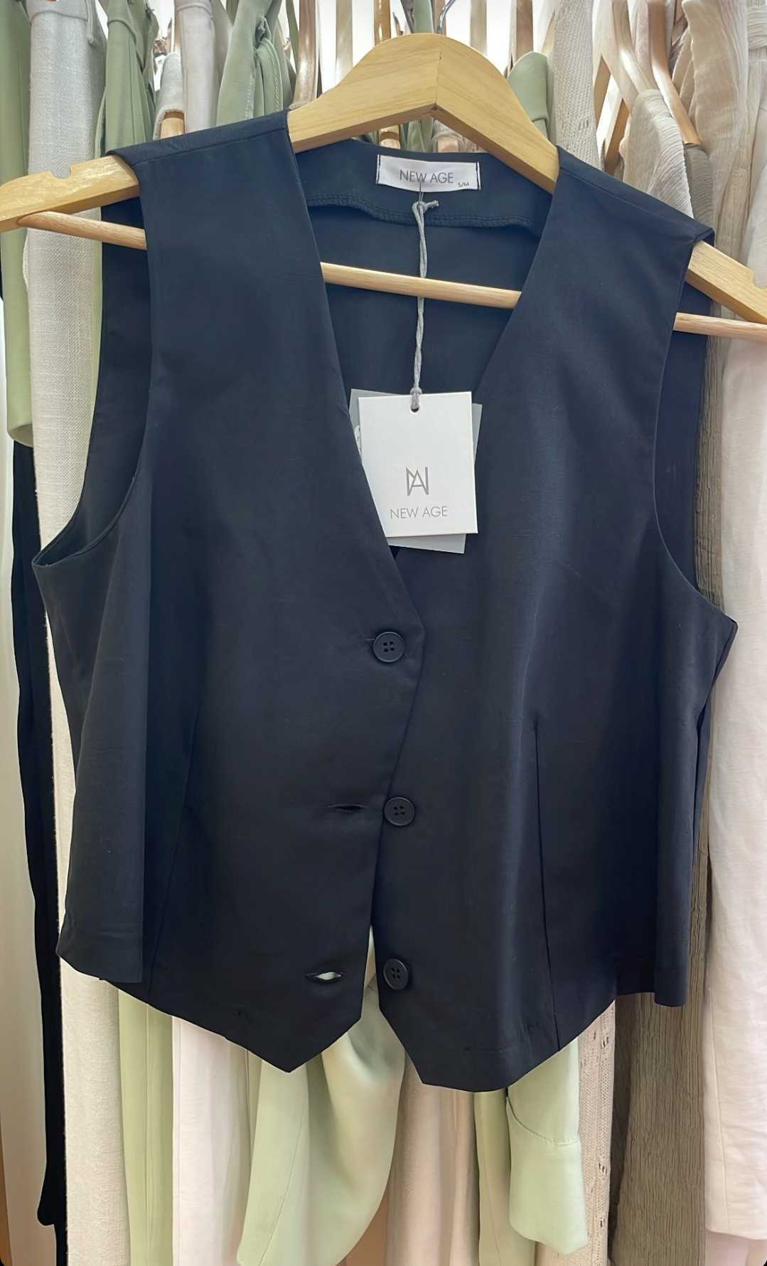 Navy blue vest on a hanger with a visible brand tag against a clothing rack background.