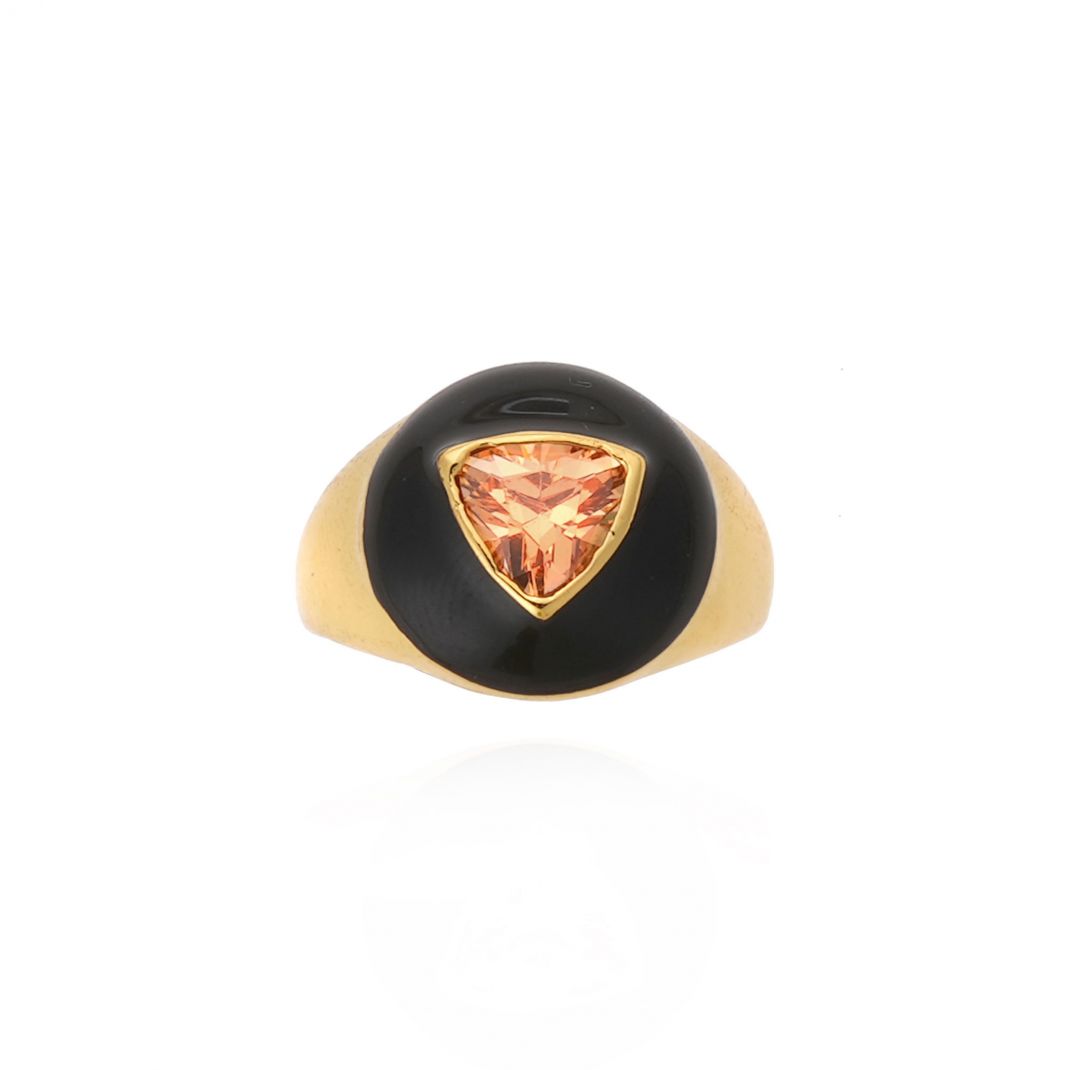 Gold ring with a black bezel and orange gemstone on a white background