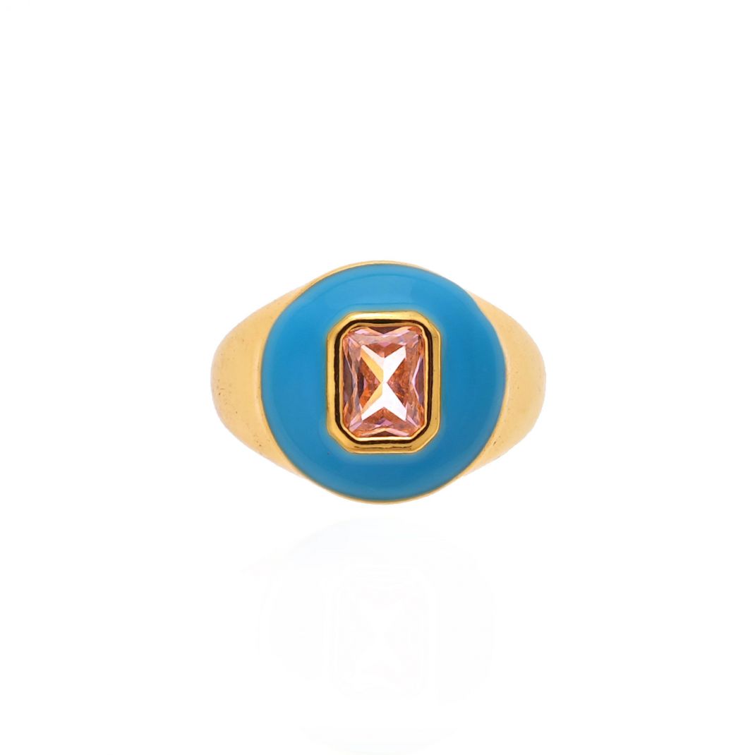 Gold ring with a blue circular band and pink gemstone on a white background