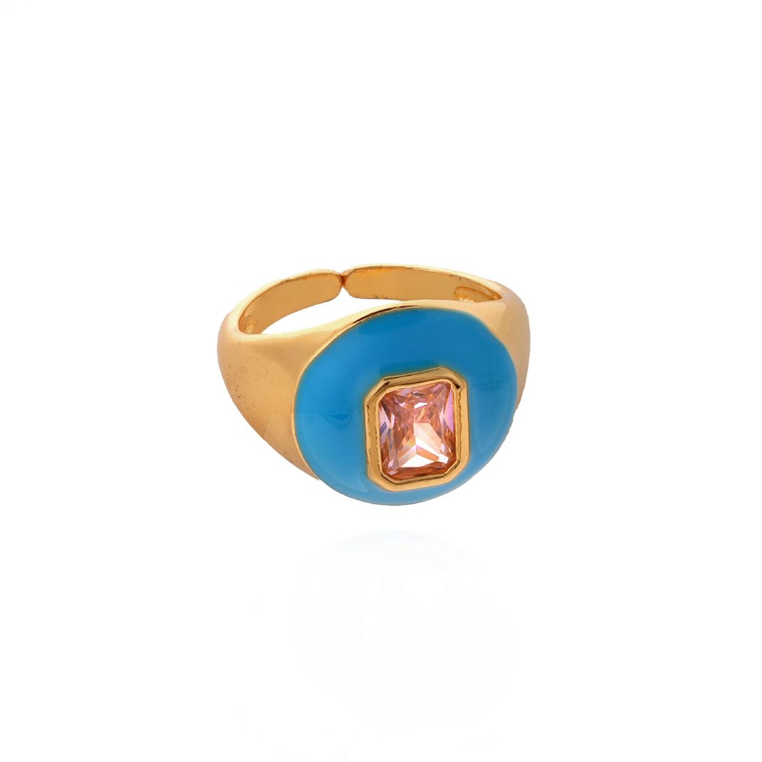 Gold ring with a blue bezel and pink gemstone on a white background