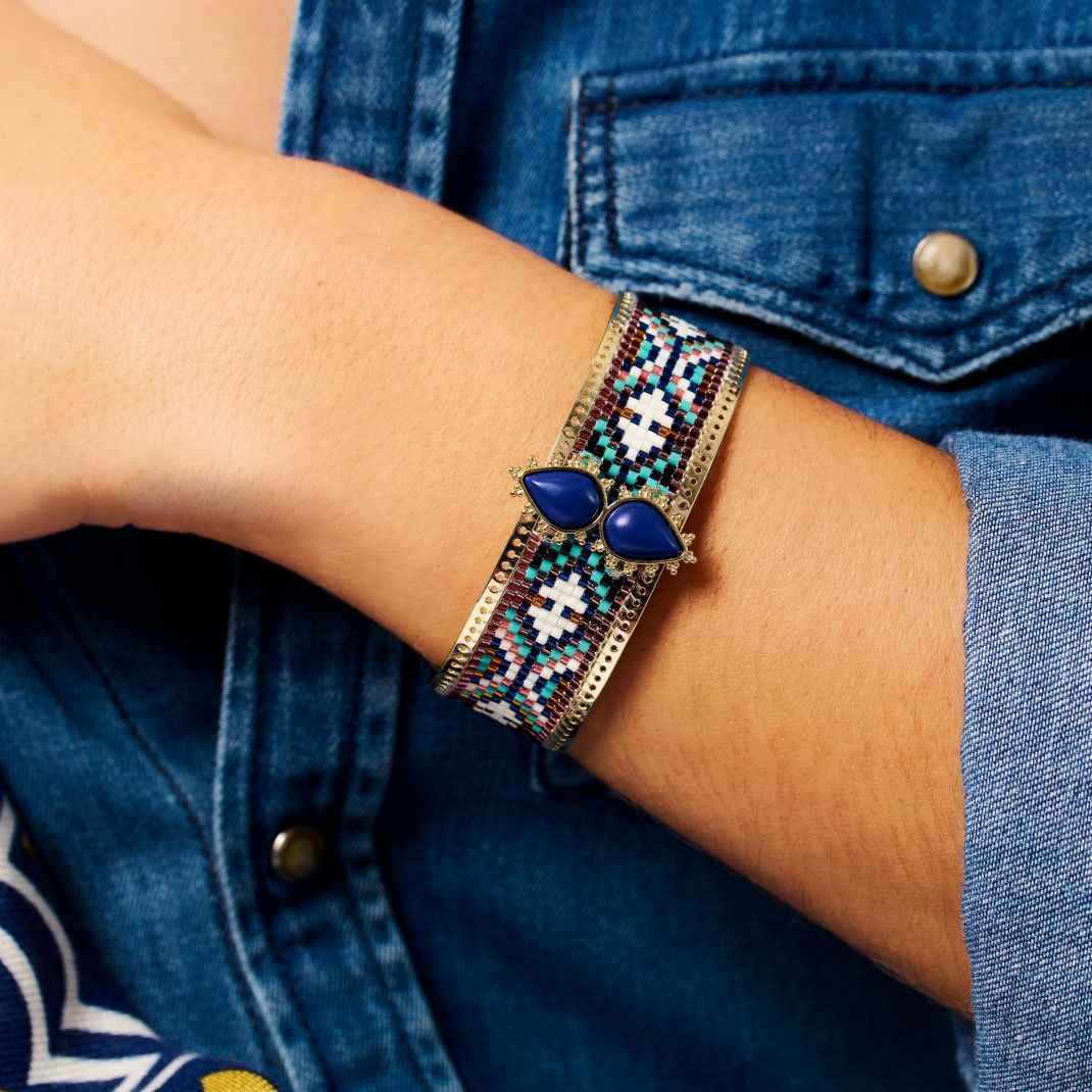Beaded bracelet with blue stones on a wrist against a denim background