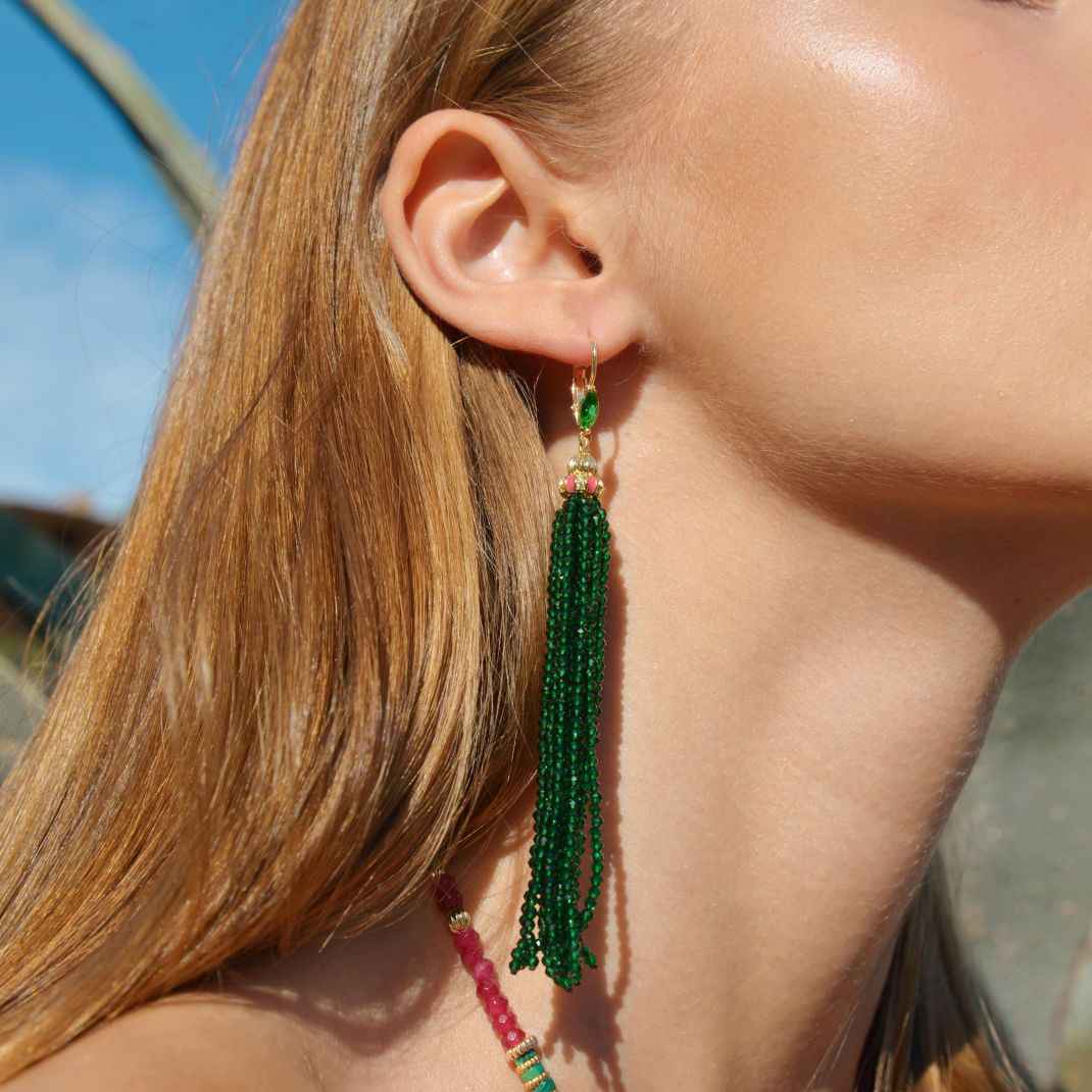 Close-up of a person wearing green beaded earrings with a blurred background
