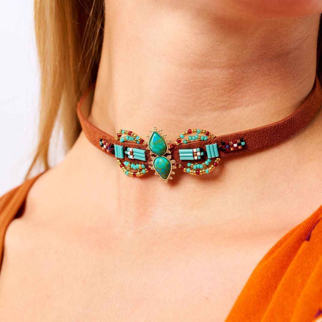 Necklace with turquoise stones and brown leather strap worn by a person