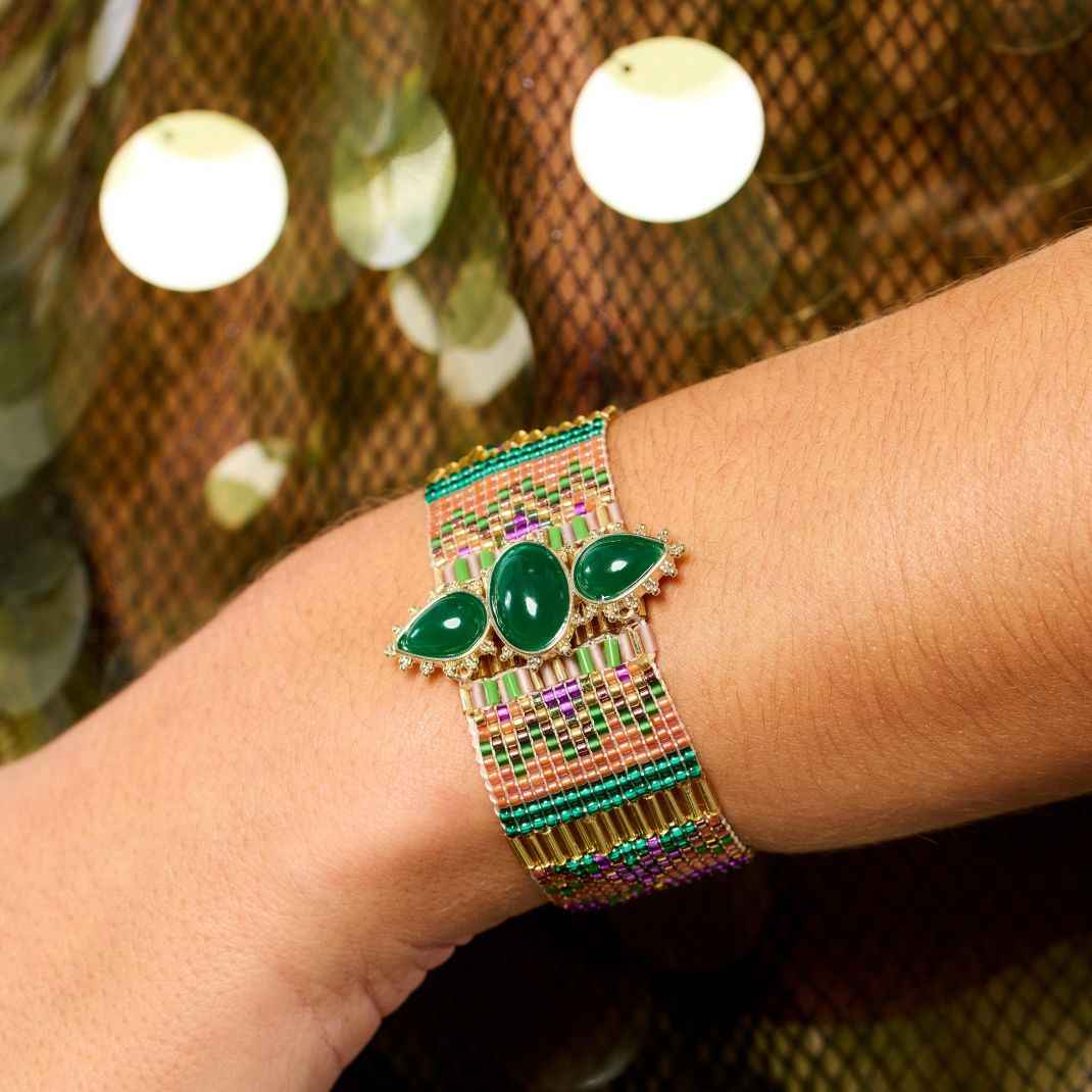 Bracelet with green stones on a wrist against a blurred background