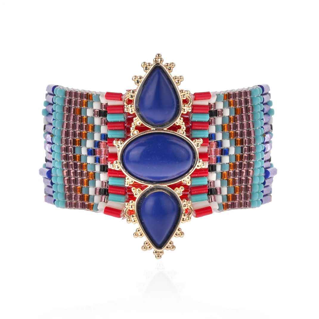 Multicolored beaded bracelet with blue teardrop stones on a white background