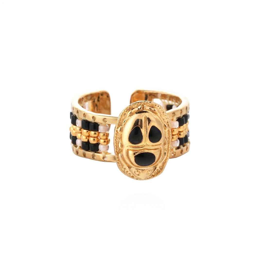 Gold and black beaded ring on a white background