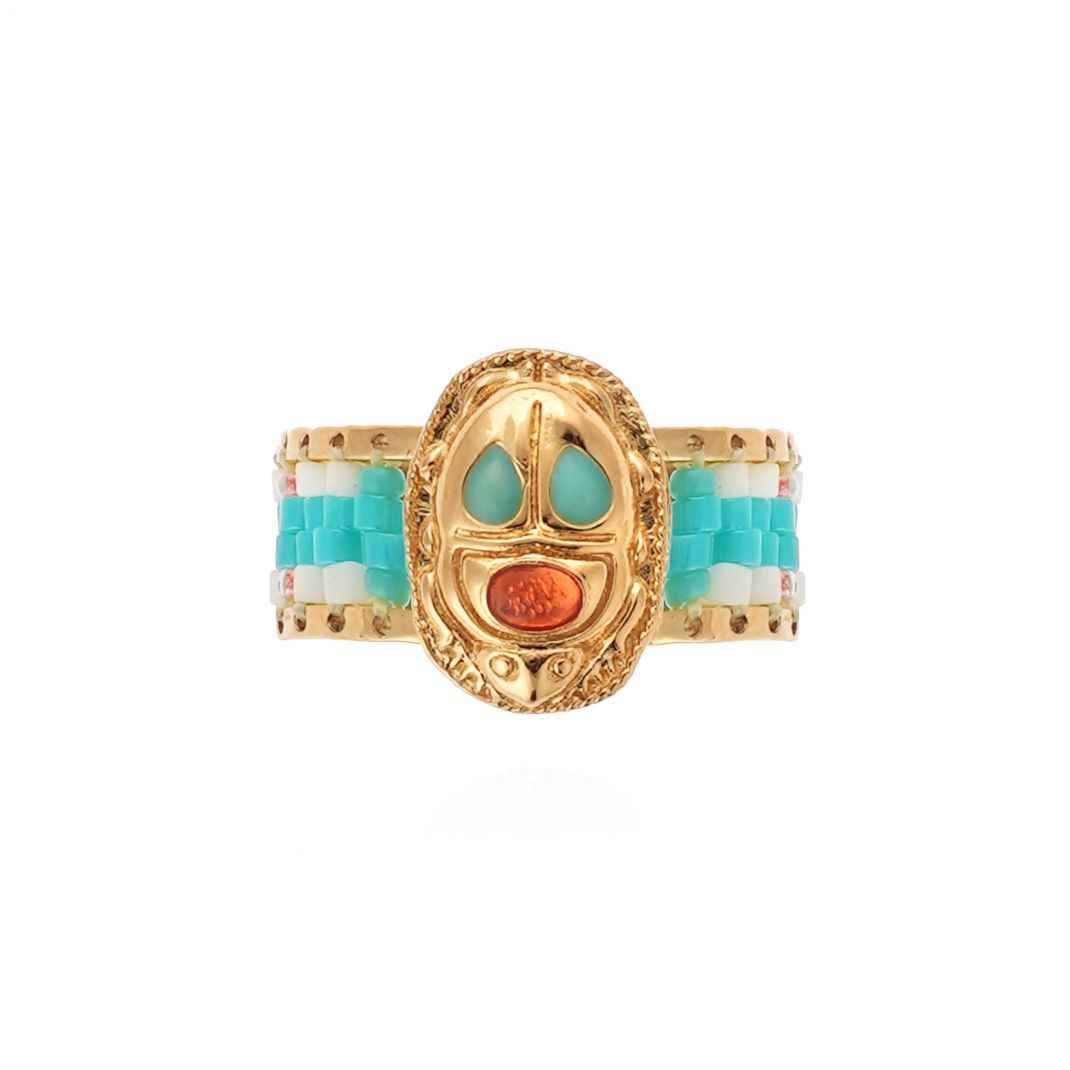 Gold ring with turquoise and coral accents on a white background