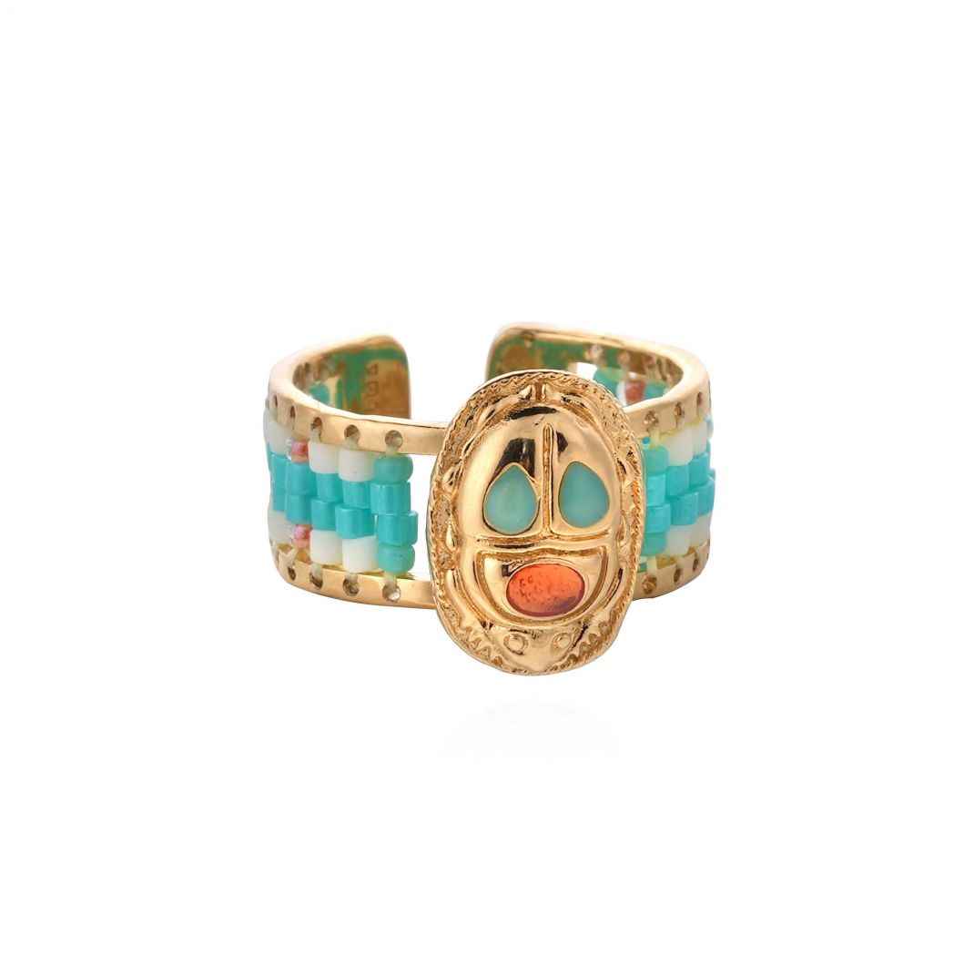 Gold ring with colorful beaded band on a white background