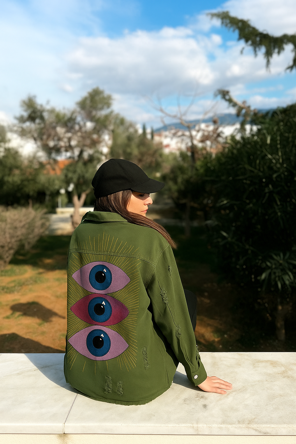 Person wearing a green "Eye" see you jacket with eye designs outdoors