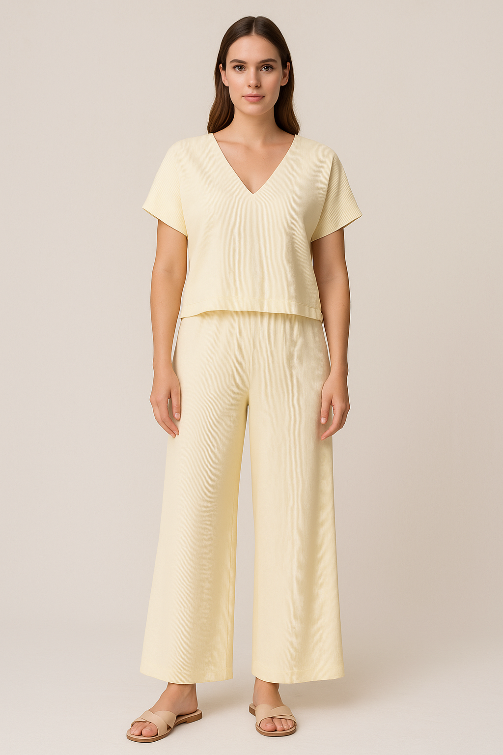Woman wearing a light yellow top and wide-leg pants on a plain background