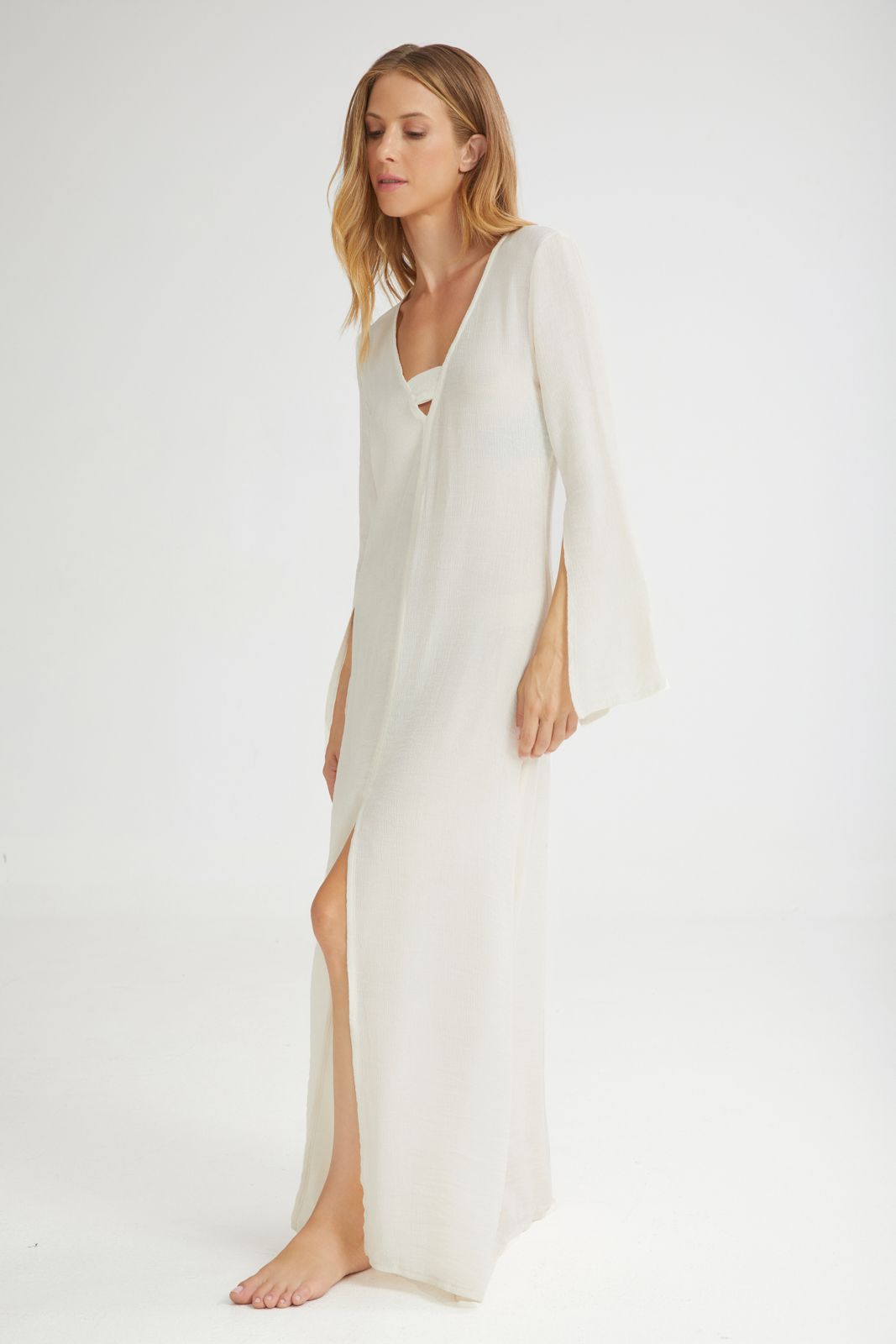 Woman wearing a long white dress with a V-neckline on a white background