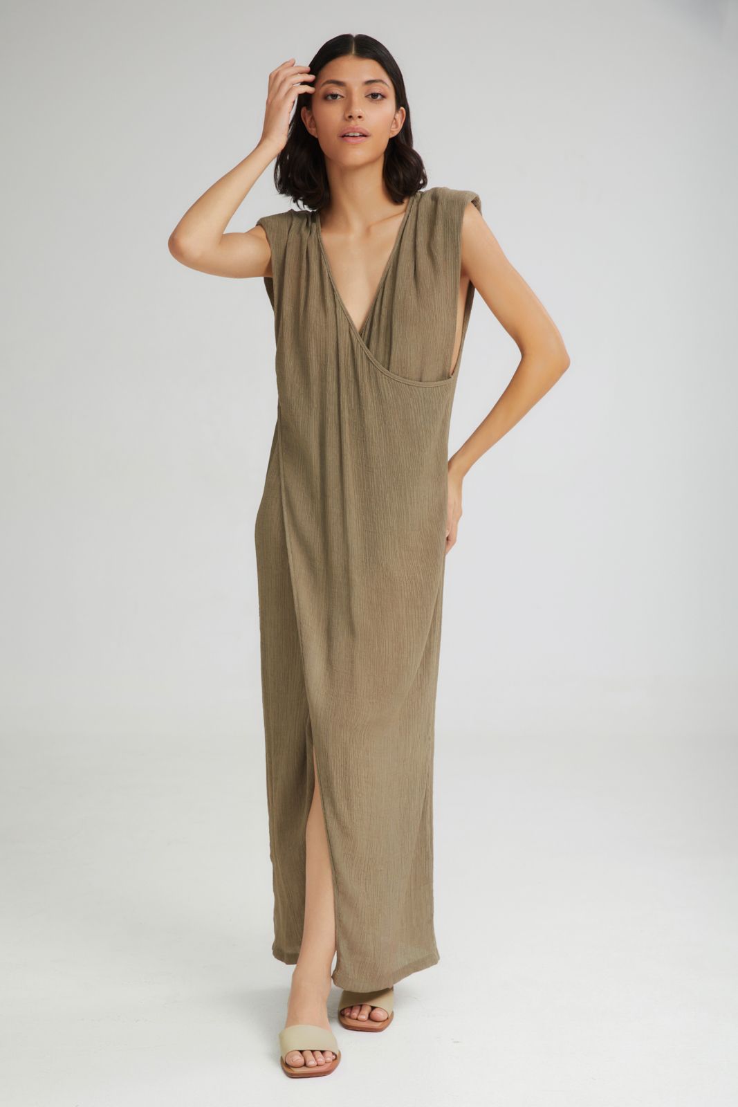 Woman wearing a long olive green dress on a white background