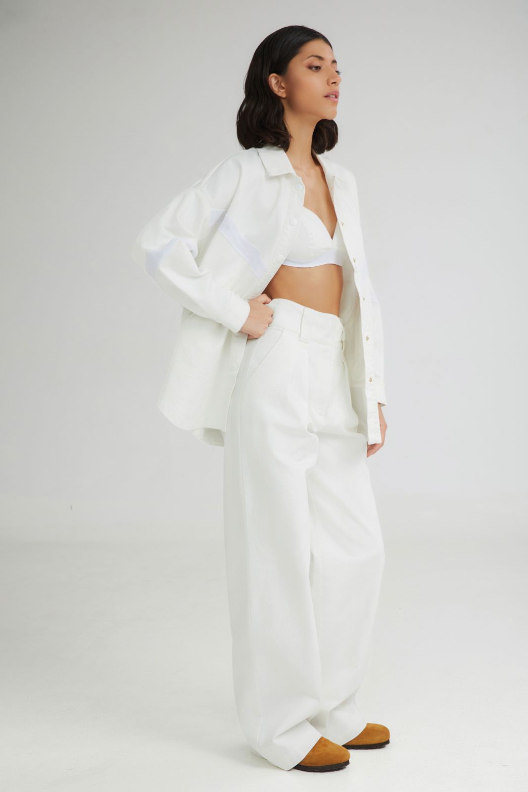 Woman wearing a white outfit with a jacket and pants on a plain background