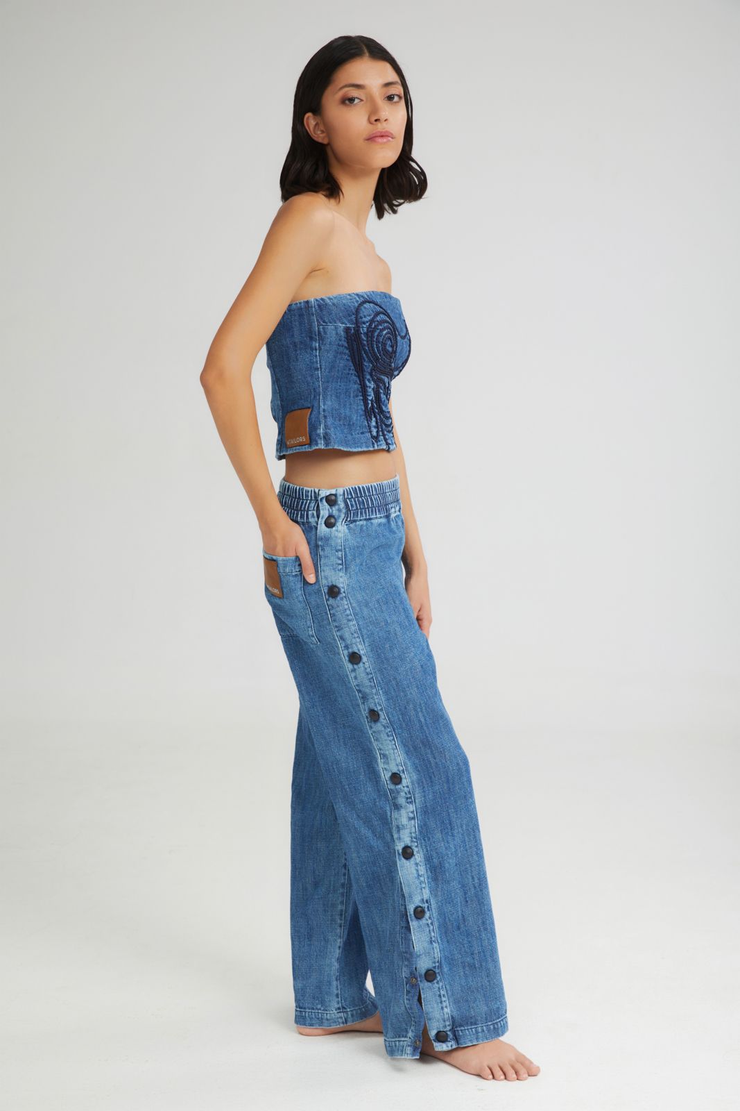 Woman wearing a denim outfit with wide-leg pants and a strapless top on a white background