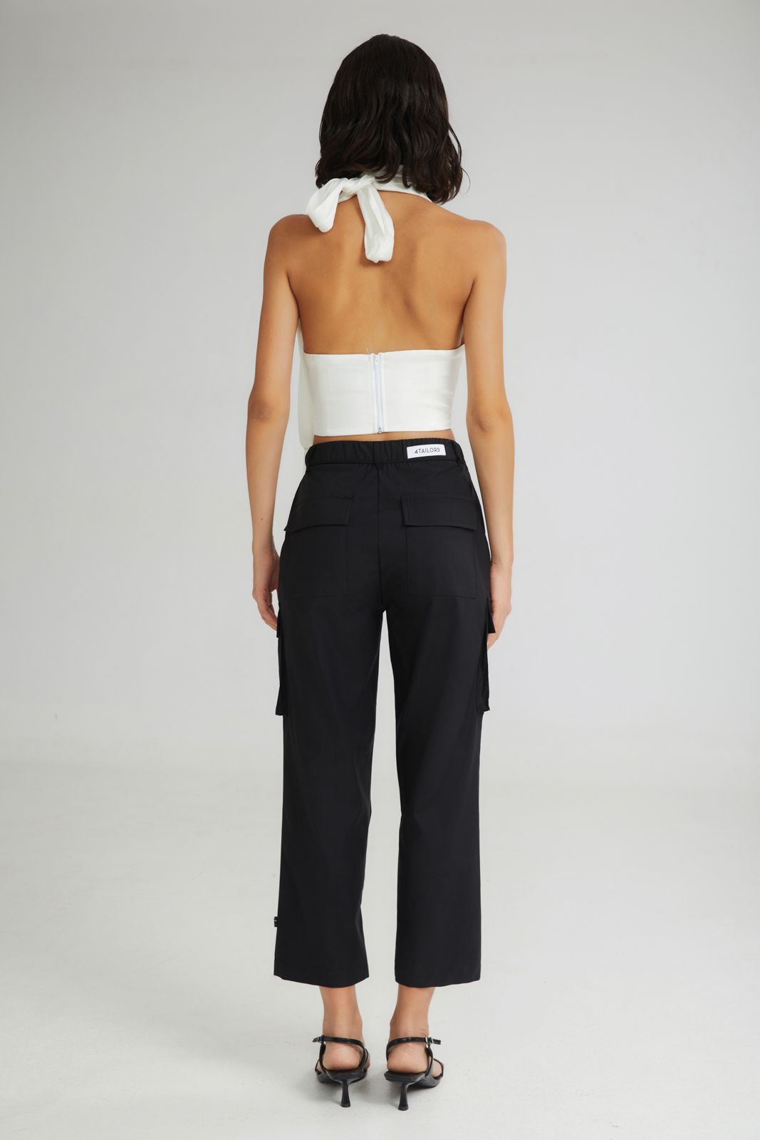 Woman wearing a white strapless top and black pants on a gray background