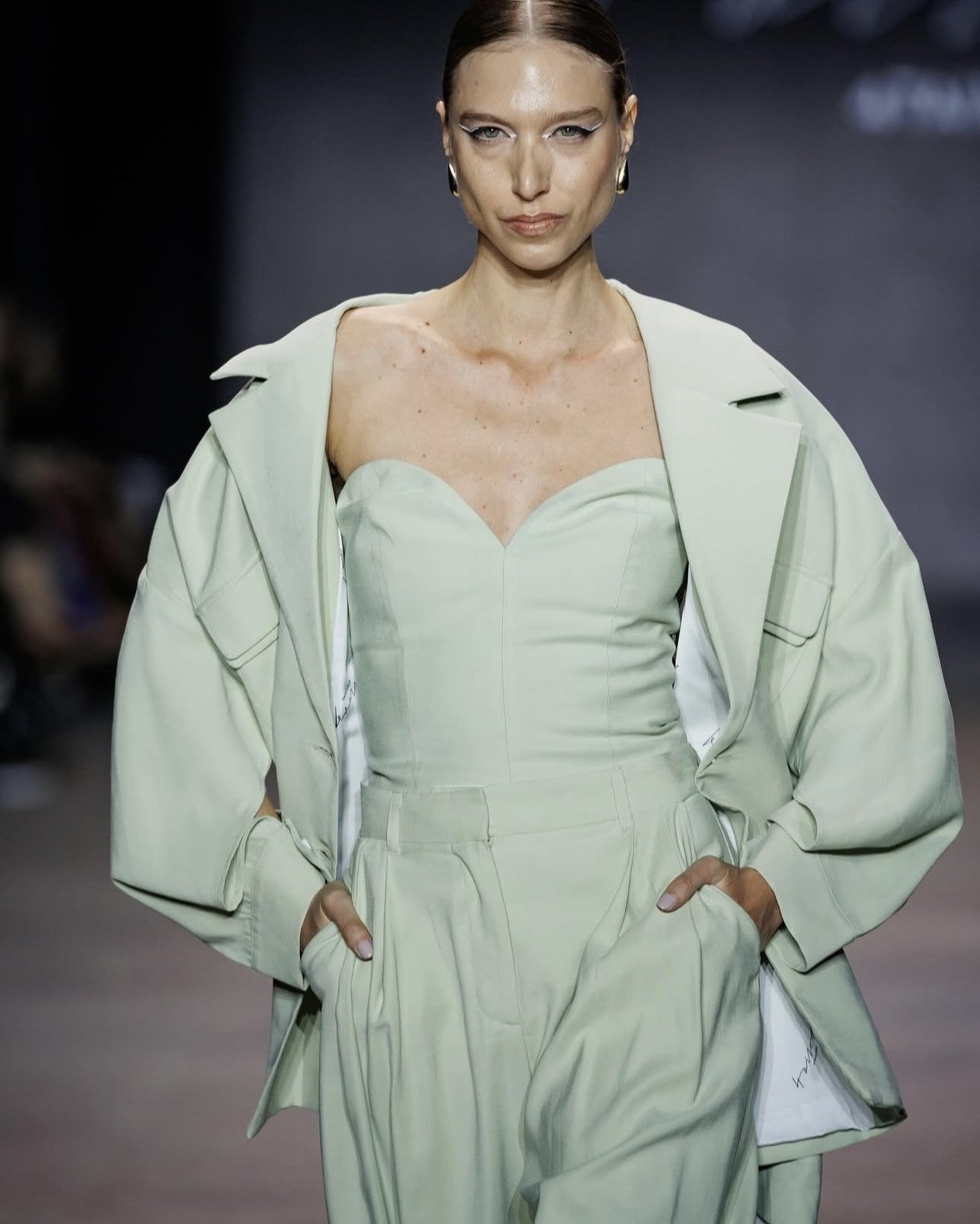 Model wearing a light green outfit on a runway