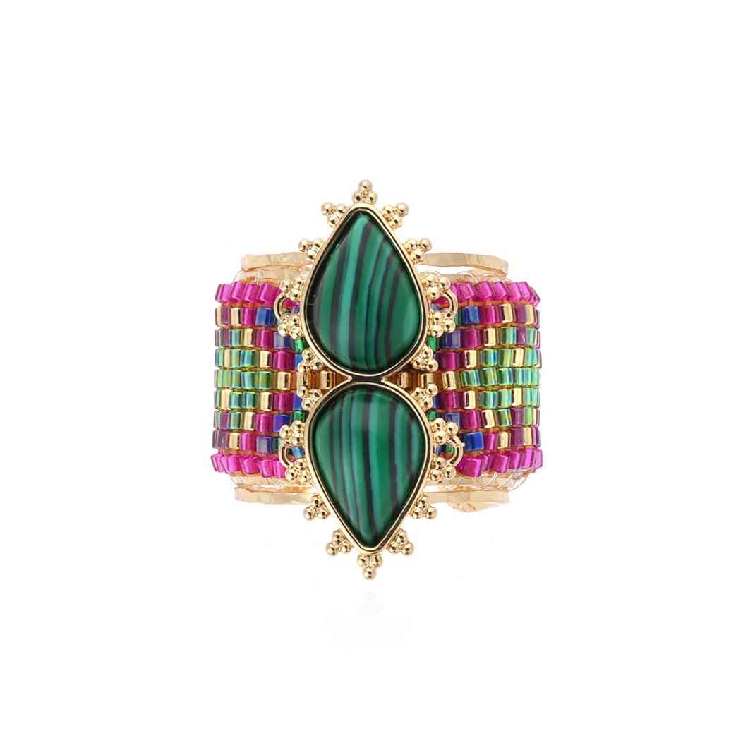 Multicolored beaded cuff bracelet with green stone on a white background