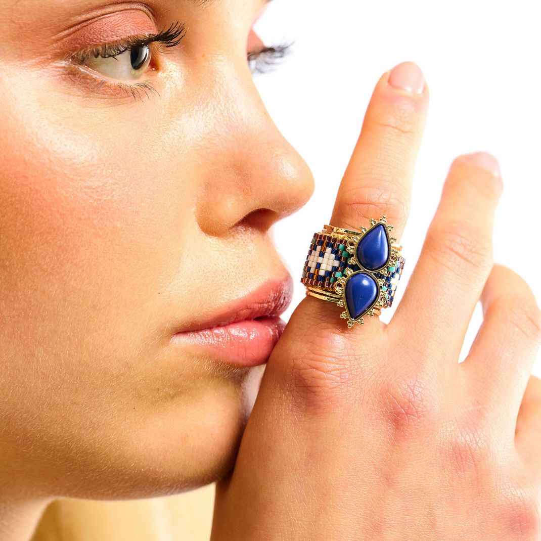 Close-up of a woman's face with a decorative ring on her finger
