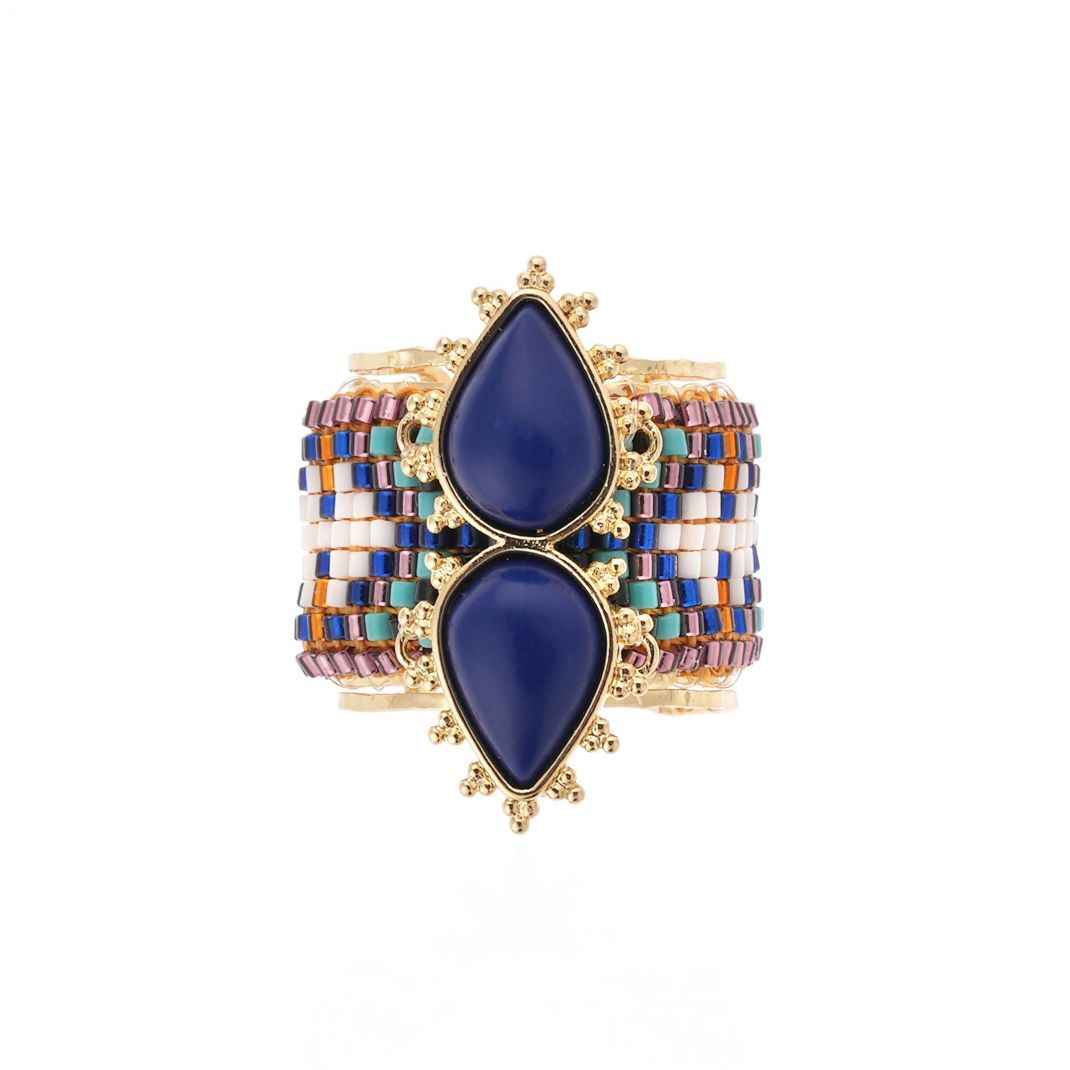 Multicolored cuff bracelet with blue teardrop stones on a white background