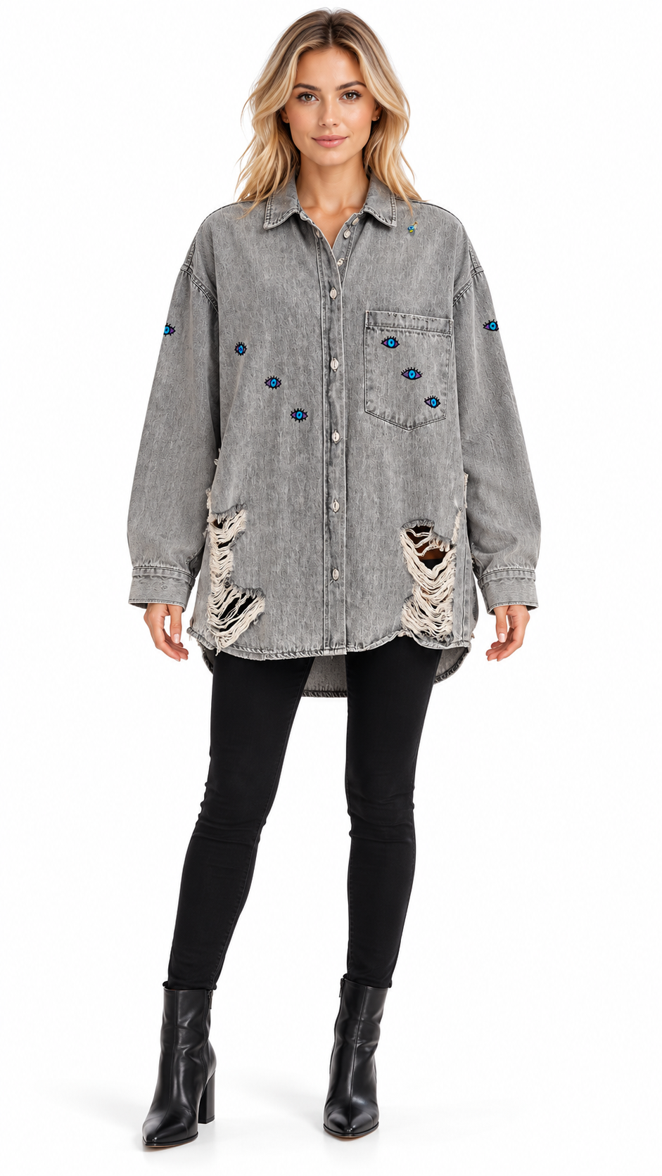 A woman modeling a distressed gray denim button-up shirt jacket with blue button accents and ripped details, paired with black skinny pants and black ankle boots, on a white studio background.