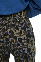 Close-up of a person wearing patterned pants with a blue top, showing the back pocket and waist area against a white background.