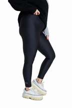 A model wearing black full-length leggings, a black fuzzy sweater, and chunky white platform sneakers, shown from the waist down against a solid white background.