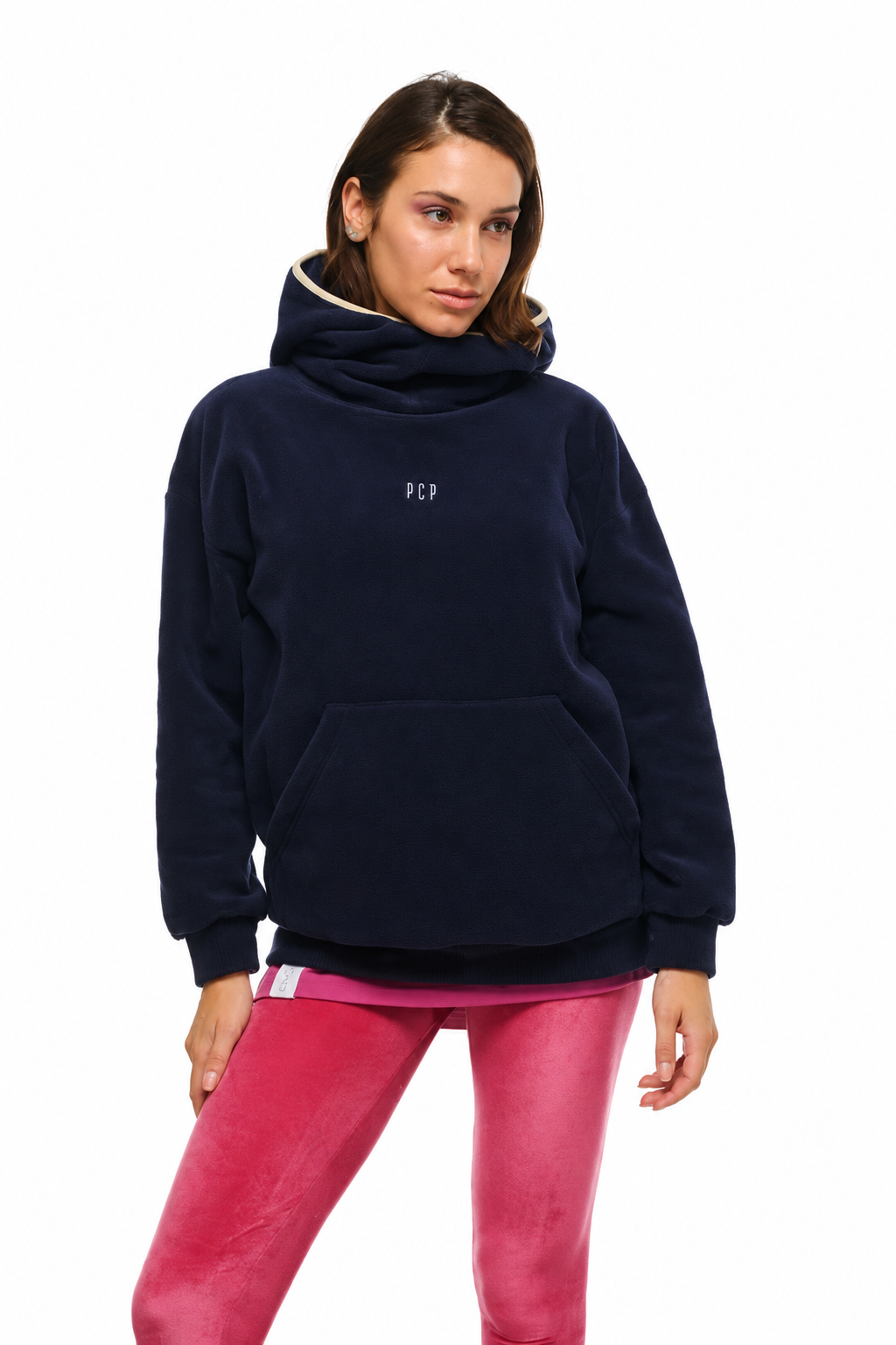 A woman modeling a navy blue fleece pullover hoodie with a small white 'PCP' logo on the chest, paired with pink leggings, against a plain white background.