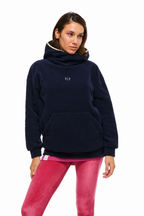 A woman modeling a navy blue fleece pullover hoodie with a small white 'PCP' logo on the chest, paired with pink leggings, against a plain white background.