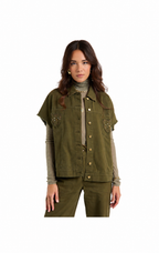 A woman modeling an olive green utility jacket with decorative metallic embroidery on the chest pockets, worn over a beige turtleneck and matching olive pants, set against a plain white background.