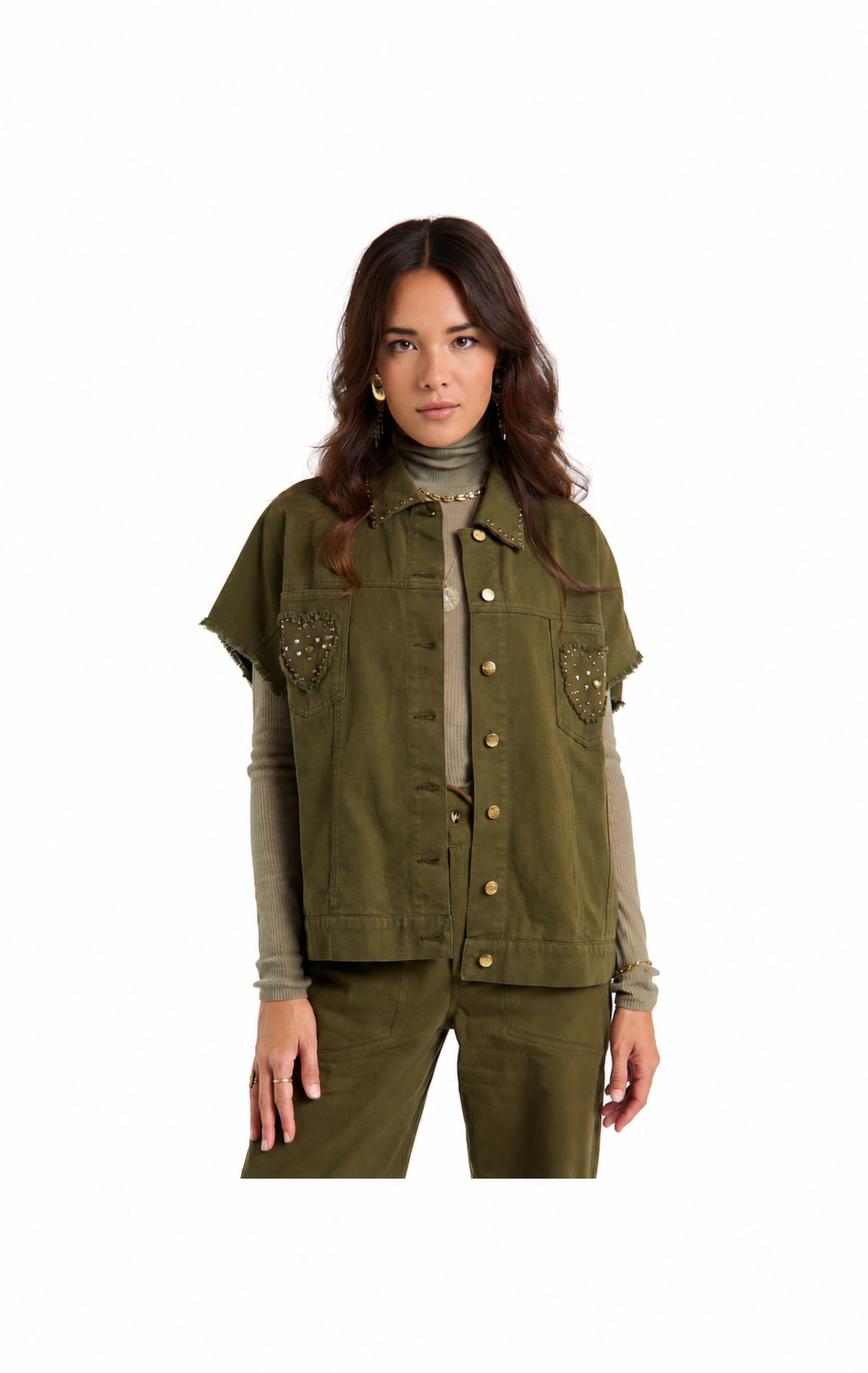 A woman modeling an olive green utility jacket with decorative metallic embroidery on the chest pockets, worn over a beige turtleneck and matching olive pants, set against a plain white background.