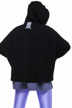 A black cropped hooded sweatshirt shown from the back on a mannequin, paired with gray shorts and purple leggings against a plain white background.