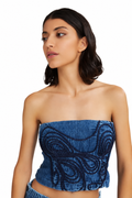 A woman wearing a blue strapless tube top with dark blue embroidered swirl patterns, photographed against a plain white background.
