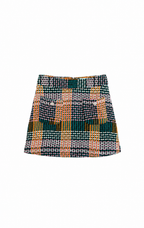 A short A-line skirt featuring a complex multicolor woven pattern with plaid and checkered blocks of green, orange, black, white, and gray, displayed flat against a solid white background.