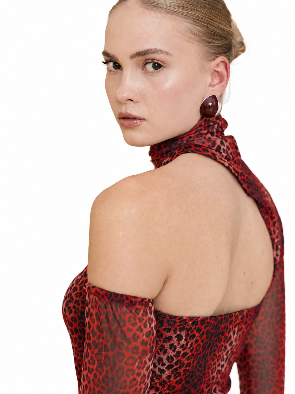 A model shown from the back and side wearing a red and black leopard print halter top with sheer long sleeves, paired with a matching high-neck scarf, against a solid white background.