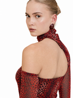 A model shown from the back and side wearing a red and black leopard print halter top with sheer long sleeves, paired with a matching high-neck scarf, against a solid white background.