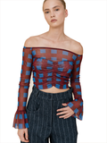 A model wearing a sheer off-the-shoulder long-sleeve crop top with a blue and burgundy checkered pattern, paired with dark pinstriped trousers, against a plain white background.