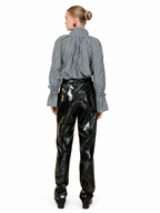 A model shown from the back wearing a gray and white vertically striped long-sleeve blouse with gathered cuffs and high-waisted, highly glossy black patent pants, set against a plain white background.