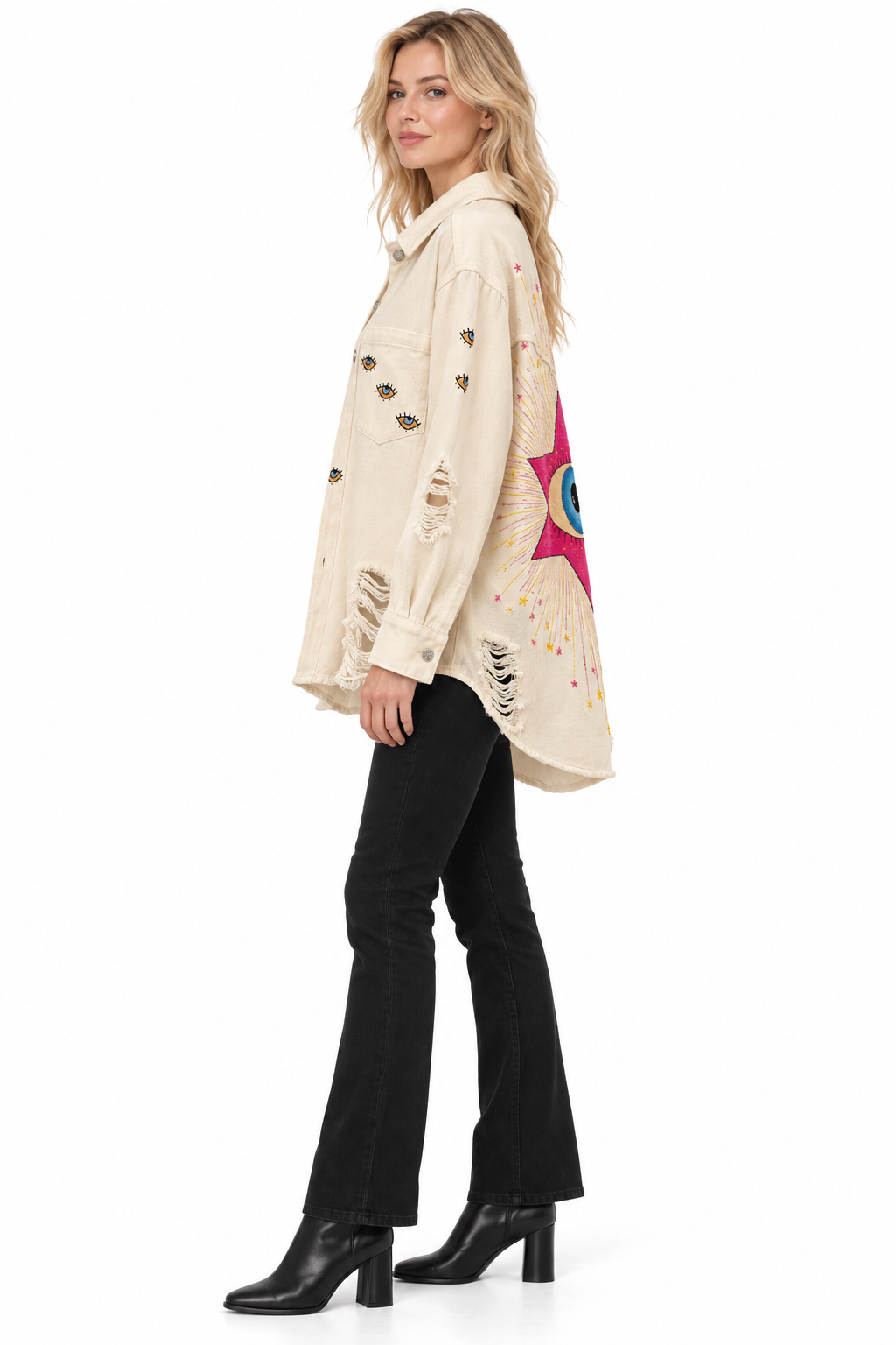 A woman modeling a distressed cream-colored denim jacket with a colorful star graphic on the back, paired with black flared jeans and black ankle boots, against a solid white background.
