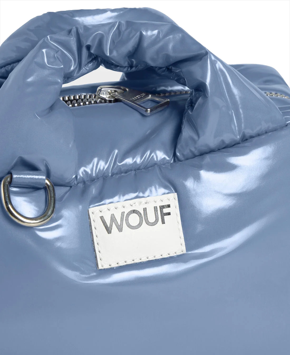 Close-up of a glossy light blue puffer-style bag with a white rectangular patch reading WOUF and a silver zipper pull.