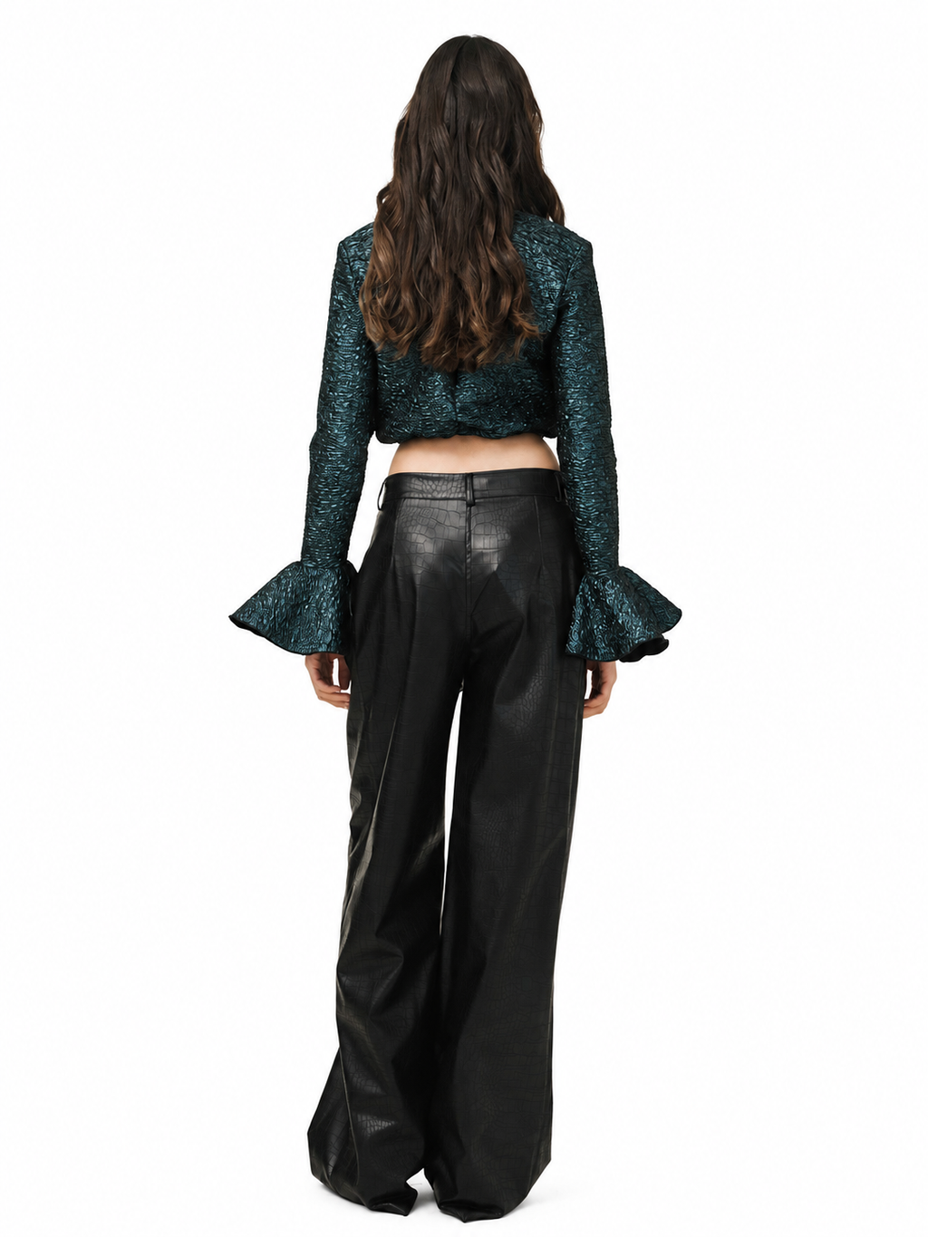 A model viewed from behind wearing a dark teal-green sequined long-sleeve crop top with flared ruffle sleeves and black wide-leg faux-leather pants, set against a plain white background.