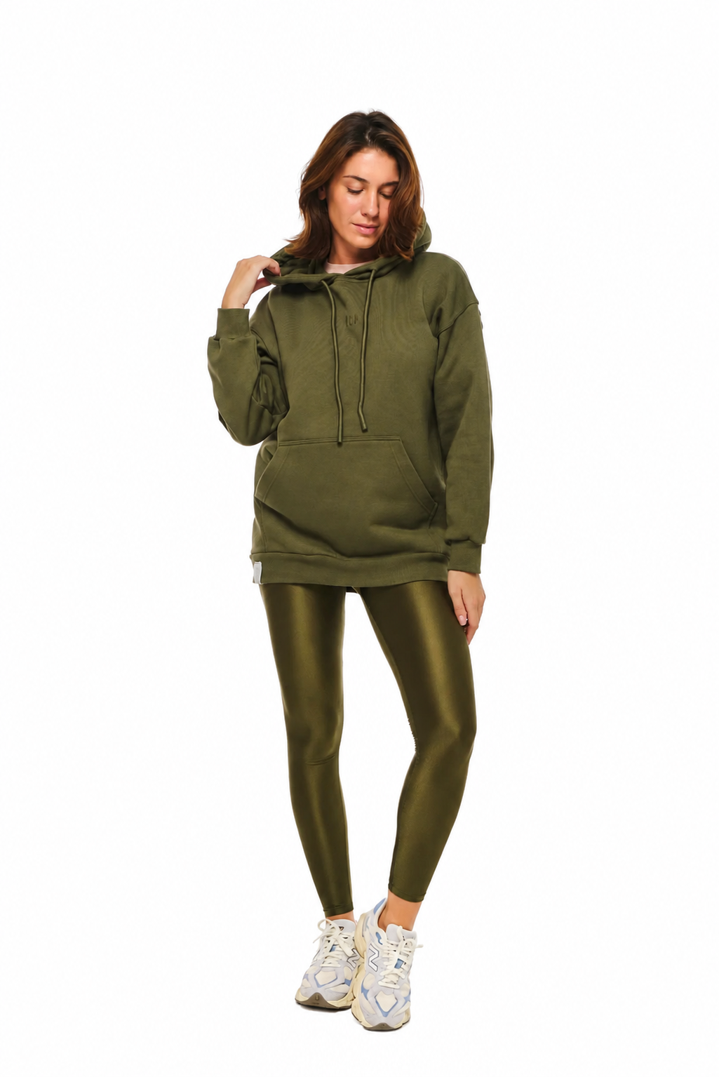 A woman modeling an olive green oversized hoodie and matching shiny olive green leggings against a plain white background.